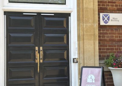 Front doors of St. Hugh's College with a sign that readsd "Oxford Scholars Programme"