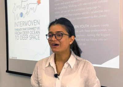 Designer Anurita Chandola speaking during a Moon habitat design workshop in front of an INTERWOVEN presentation screen.