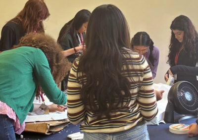 A group of international students collaborating around a table to build Moon habitat prototypes using craft supplies.