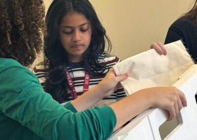 Two students attaching textile material to a white foam model frame during the Moon habitat ART challenge workshop.