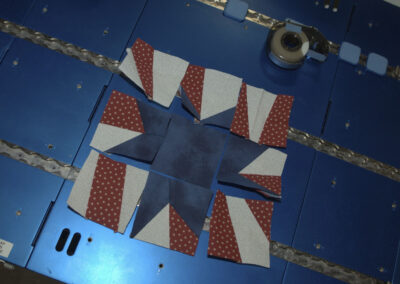 Fabric pieces of astronaut Karen Nyberg's star quilt block laid out for assembly on a blue metal workstation table aboard the International Space Station.