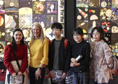 Astronaut Dr. Karen Nyberg posing with attendees in front of the large Artemis-inspired Lunar Quilts installation at the Earth to Space festival.